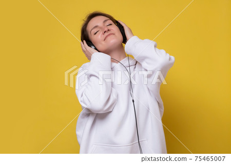 Pretty young smiling girl enjoys listening music. 75465007