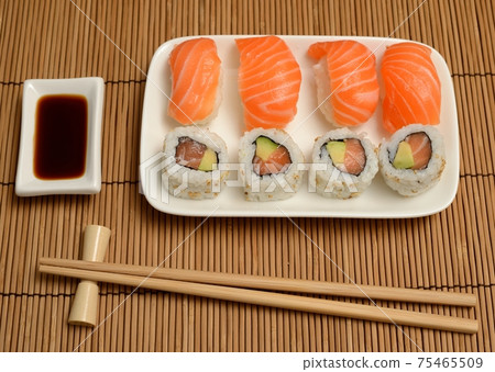 chopsticks, soy sauce and sushi on the mat 75465509