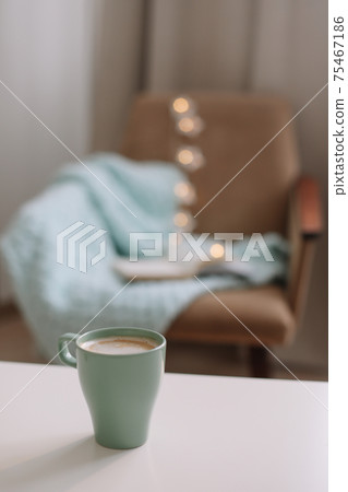 Cozy home interior with cup of coffee, book and armchair Cozy home interior with cup of coffee, book and armchair 75467186