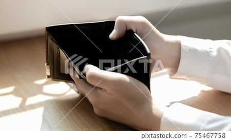 Young man's hand was carrying a black leather bag with no dollar bills, nothing in the bag, Poverty, No money, Driving money, Economic crash, Poor money management, Money management mistakes. 75467758