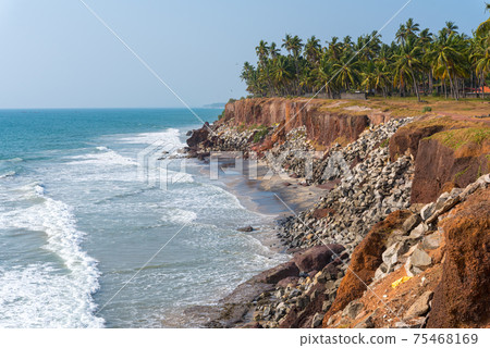Scenery of coastline in famous Varkala, Kerala, India. Edava village, 2 km away to North from resort Varkala. Shore protection measures - steep coastline strengthened with stones. Scenery of coastline in famous Varkala, Kerala, India. Edava village, 2 km away to North from resort Varkala. Shore protection measures - steep coastline strengthened with stones. 75468169