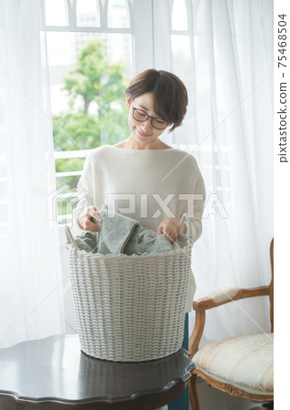 Short-haired housewife doing household chores with laundry Short-haired housewife doing household chores with laundry 75468504