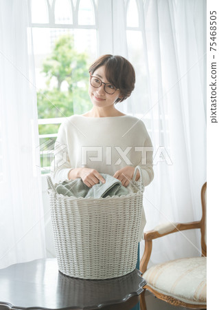Short-haired housewife doing household chores with laundry Short-haired housewife doing household chores with laundry 75468505
