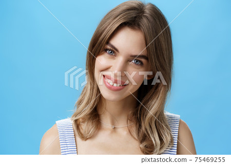 Waist-up shot of charming self-assured authentic woman feeling great accepting own imperfections tilting head smiling broadly at camera and showing cute gapped teeth posing over blue background Waist-up shot of charming self-assured authentic woman feeling great accepting own imperfections tilting head smiling broadly at camera and showing cute gapped teeth posing over blue background 75469255