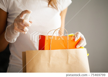 Close up of woman in protective gloves disinfecting shopping Close up of woman in protective gloves disinfecting shopping 75469799
