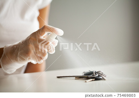 Woman disinfecting keys with disinfectant on the table Woman disinfecting keys with disinfectant on the table 75469803