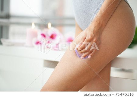 Woman getting anti-cellulite massage of hips with use of vacuum cans in beauty studio Woman getting anti-cellulite massage of hips with use of vacuum cans in beauty studio 75470116