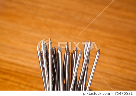Metal iron pointed nail on walnut wood in, isolated on wooden background 75470581