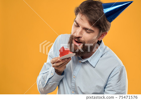 a man with a birthday cake in his hands and in a cap on a yellow background on his birthday a man with a birthday cake in his hands and in a cap on a yellow background on his birthday 75471576