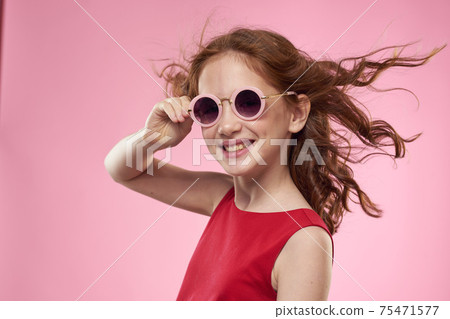 Cheerful little girl childhood dark glasses red dress lifestyle pink background Cheerful little girl childhood dark glasses red dress lifestyle pink background 75471577