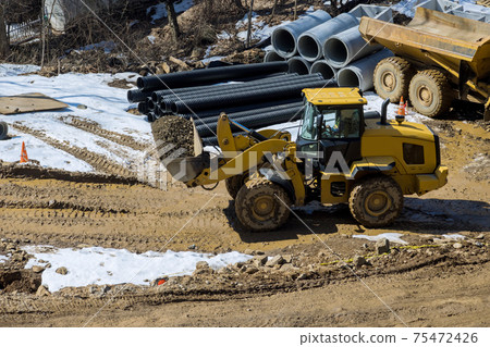 Heavy excavator excavating soil working during road works, moving gravel during construction of the new road 75472426