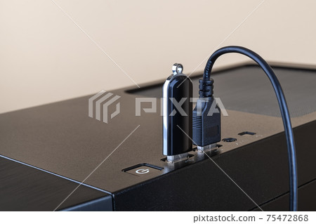 USB flash drive and USB cable both inserted into ports on the top of a computer tower case. 75472868