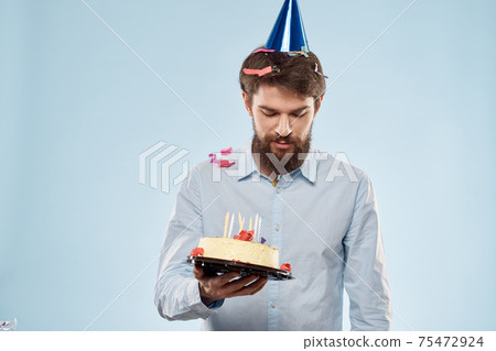 cake in a plate and birthday man with a cap on his head blue backgroun 75472924