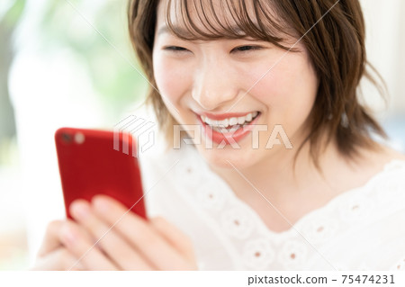 A young woman watching a smartphone A young woman watching a smartphone 75474231