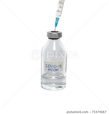 A syringe sticks out in a bottle of vaccine covid-19 75474867