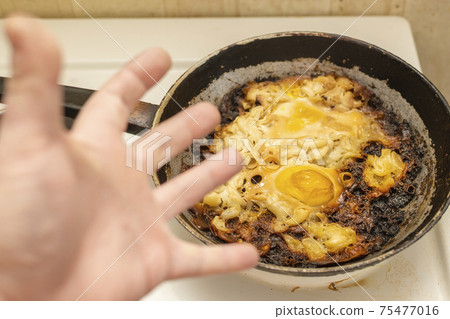 view of overcooked, burnt eggs, omelet in an old cast iron frying pan view of overcooked, burnt eggs, omelet in an old cast iron frying pan 75477016