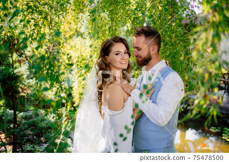 groom in blue suit and bride with curls of stand in willow 75478500