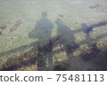 Shadows of parents and children reflected in the shallow sea 75481113
