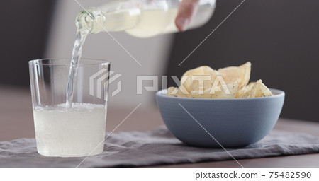 man pour ginger beer into tumbler glass with blue bowl full of potato chips man pour ginger beer into tumbler glass with blue bowl full of potato chips 75482590