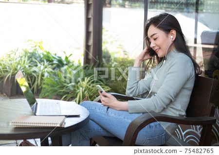 Happiness Asian woman listening music and using laptop at coffee shop. Relaxing time, Happiness Asian woman listening music and using laptop at coffee shop. Relaxing time, 75482765
