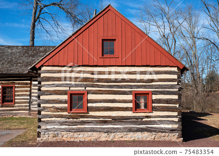 Red peaked roof and log construction of a colonial house Red peaked roof and log construction of a colonial house 75483354