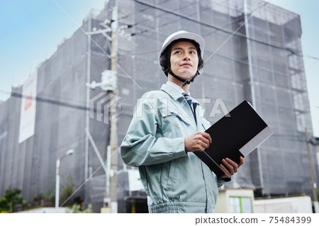 A man in work clothes standing at a construction site 75484399