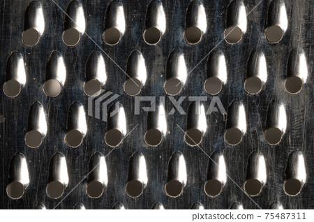 Close-up pattern of the holes of an old kitchen grater with rust elements. Grunge background 75487311