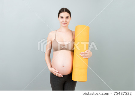 Pregnant Girl Holding Yoga Mat Standing Over Colored Background. Studio Shot, Free Space For Design Pregnant Girl Holding Yoga Mat Standing Over Colored Background. Studio Shot, Free Space For Design 75487522