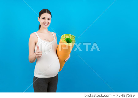 Pregnant Girl Holding Yoga Mat Standing Over Colored Background. Studio Shot, Free Space For Design Pregnant Girl Holding Yoga Mat Standing Over Colored Background. Studio Shot, Free Space For Design 75487589