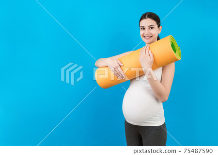 Pregnant Girl Holding Yoga Mat Standing Over Colored Background. Studio Shot, Free Space For Design Pregnant Girl Holding Yoga Mat Standing Over Colored Background. Studio Shot, Free Space For Design 75487590