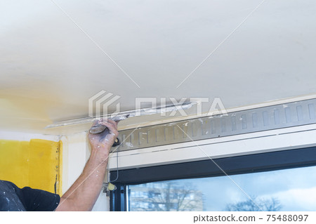 Hand of builder worker spacks ceiling with putty plaster aligning ceiling with spatula Hand of builder worker spacks ceiling with putty plaster aligning ceiling with spatula 75488097