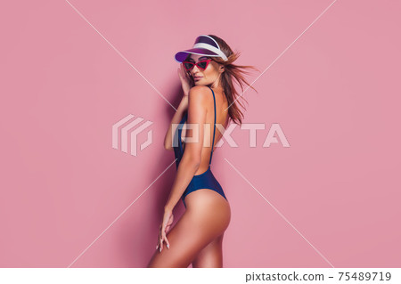 Woman in plastic cap visor and swimwear on pink 75489719