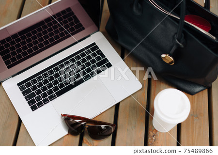 The laptop with the woman's purse and coffee outdoors The laptop with the woman's purse and coffee outdoors 75489866