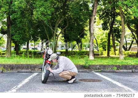 Bike life Senior rider maintaining a bike Bike life Senior rider maintaining a bike 75490257