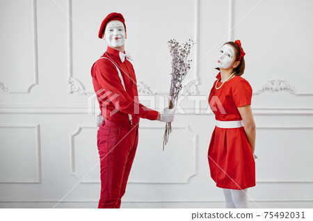 Mime artists in red costumes, scene with bouquet 75492031