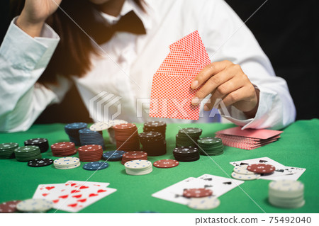 Women dealer or croupier shuffles poker cards in a casino on the background of a table, poker game concept 75492040
