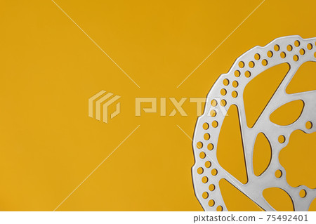 New brake disc for bicycle hydraulic brakes with yellow background and copy space New brake disc for bicycle hydraulic brakes with yellow background and copy space 75492401