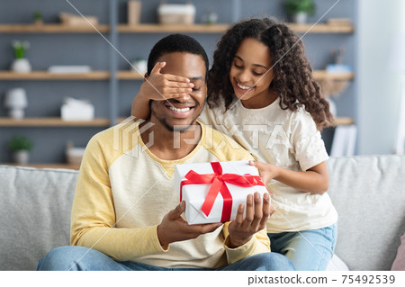 Happy little daughter giving present to her dad Happy little daughter giving present to her dad 75492539