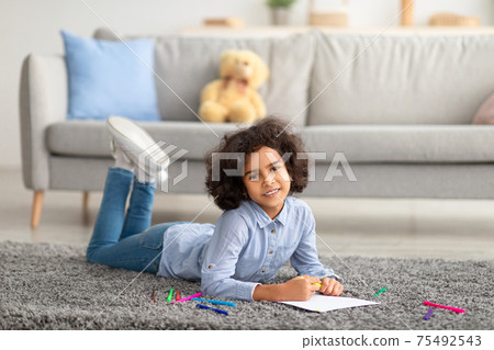 African American girl drawing on paper with colorful crayons African American girl drawing on paper with colorful crayons 75492543