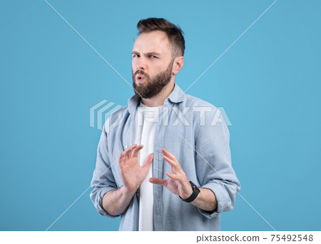 Disgusted young guy refusing something, gesturing NO or STOP over blue studio background 75492548