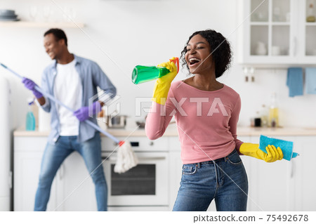 Black lady having fun with her boyfriend while cleaning kitchen 75492678