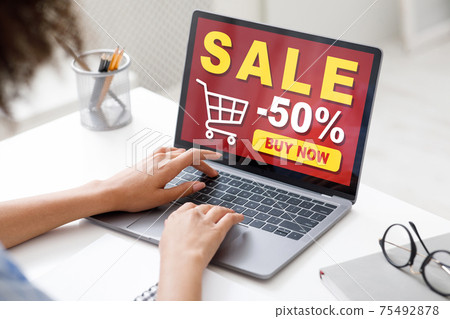Black lady sitting in office, shopping online, using laptop 75492878