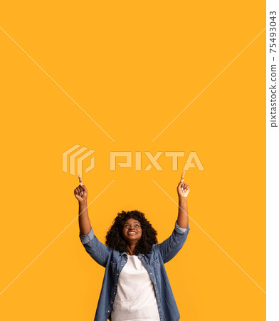 Happy black woman pointing up at copy space 75493043