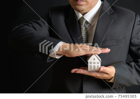 Paper house is covered by business man hands of a real estate agent to protect the house for customers, Paper house is covered by business man hands of a real estate agent to protect the house for customers, 75495305