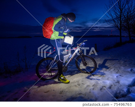 Winter extreme cyclist shines into map directly with smartphone, Winter extreme cyclist shines into map directly with smartphone, 75496763