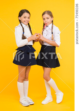 Feeling healthy is wonderful. Thirsty school girls on yellow Feeling healthy is wonderful. Thirsty school girls on yellow 75498106