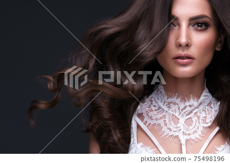 Beautiful brown-haired girl with a perfectly curls hair, and classic make-up. Beauty face and hair. 75498196