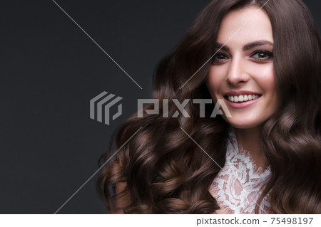 Beautiful brown-haired girl with a perfectly curls hair, and classic make-up. Beauty face and hair. 75498197
