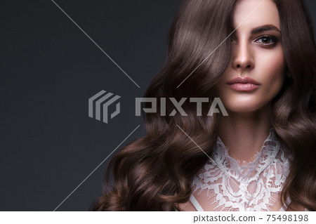 Beautiful brown-haired girl with a perfectly curls hair, and classic make-up. Beauty face and hair. 75498198