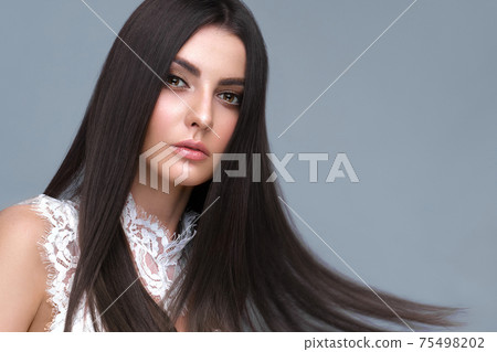 Beautiful brown-haired girl with a perfectly smooth hair, and classic make-up. Beauty face and hair. 75498202